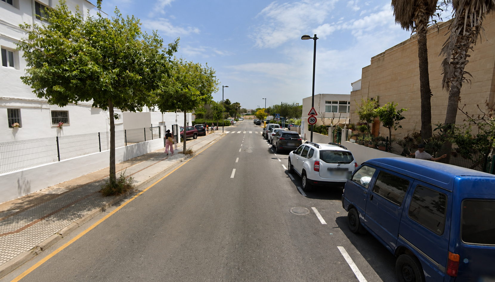 Residentiële straat in Ibiza met geparkeerde auto's en palmen