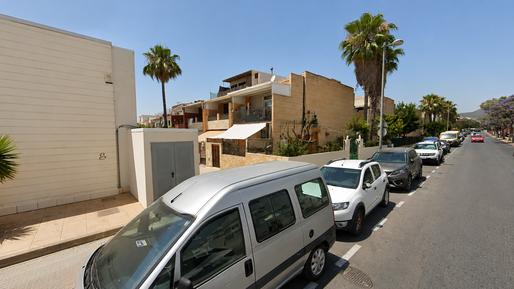 Residentiële straat in Ibiza met palmbomen en geparkeerde auto's