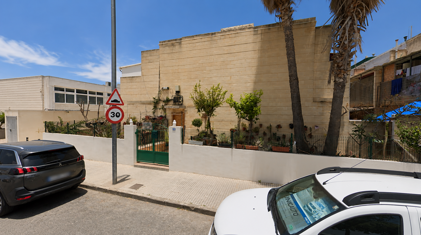 Woning met ommuurde tuin en groene poort aan een straat in Ibiza